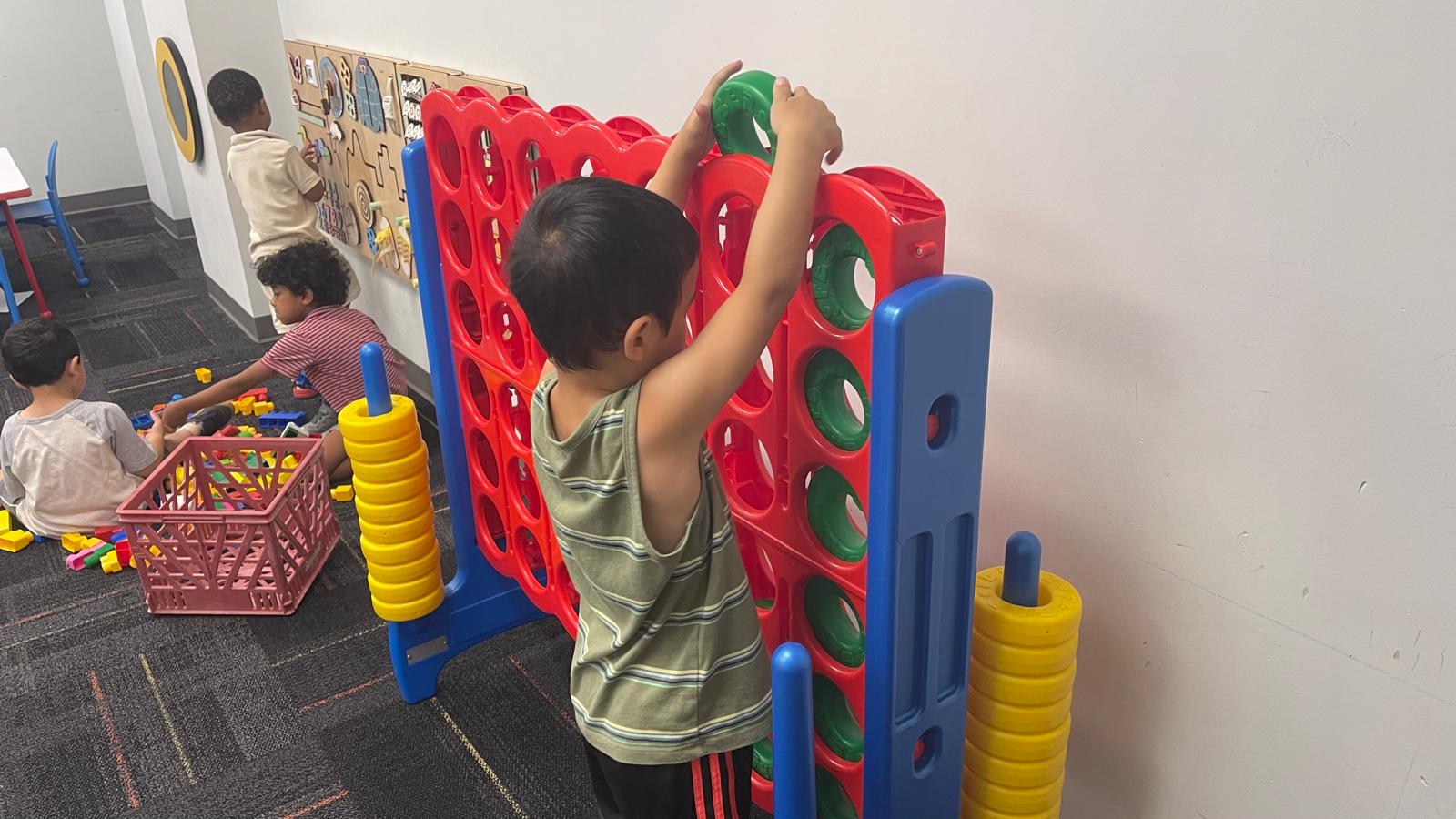 Child playing a giant connect-four game in the classroom