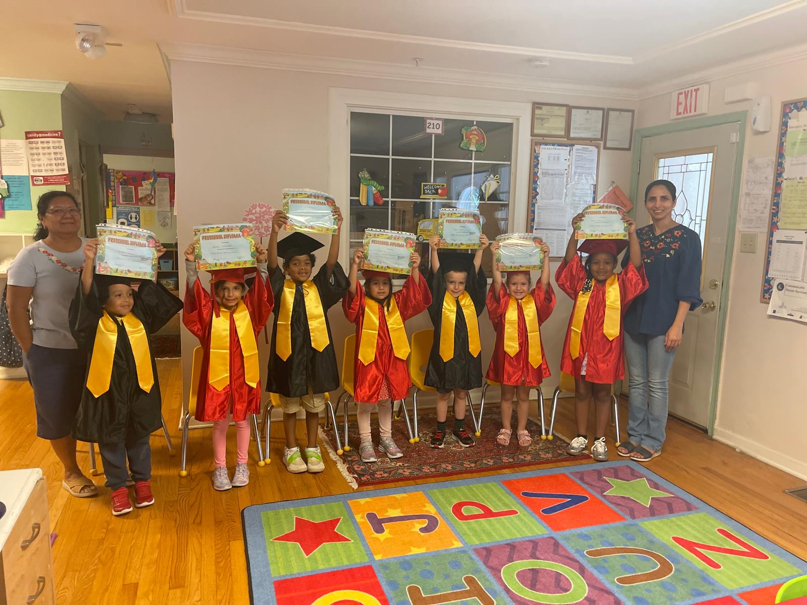 Preschool graduation class holding their diplomas with teachers