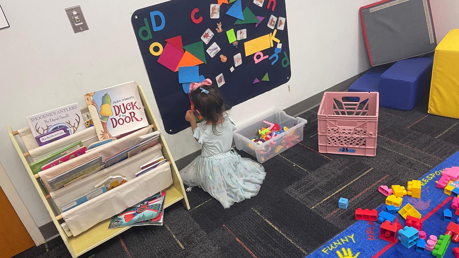 Child arranging letters and shapes on a felt learning board