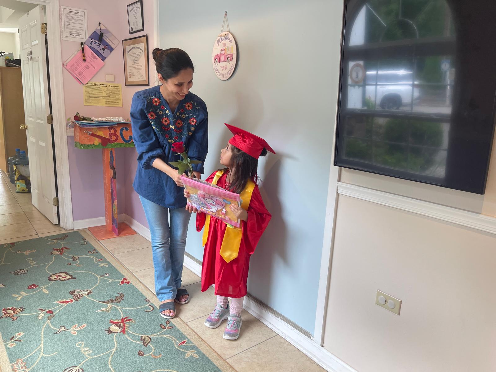 Teacher congratulating a preschool graduate with a rose