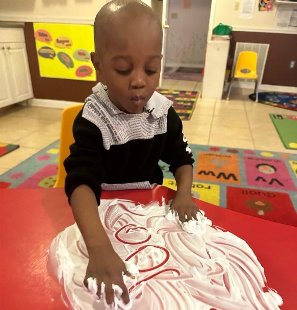 Toddler practicing letters in shaving cream during sensory play