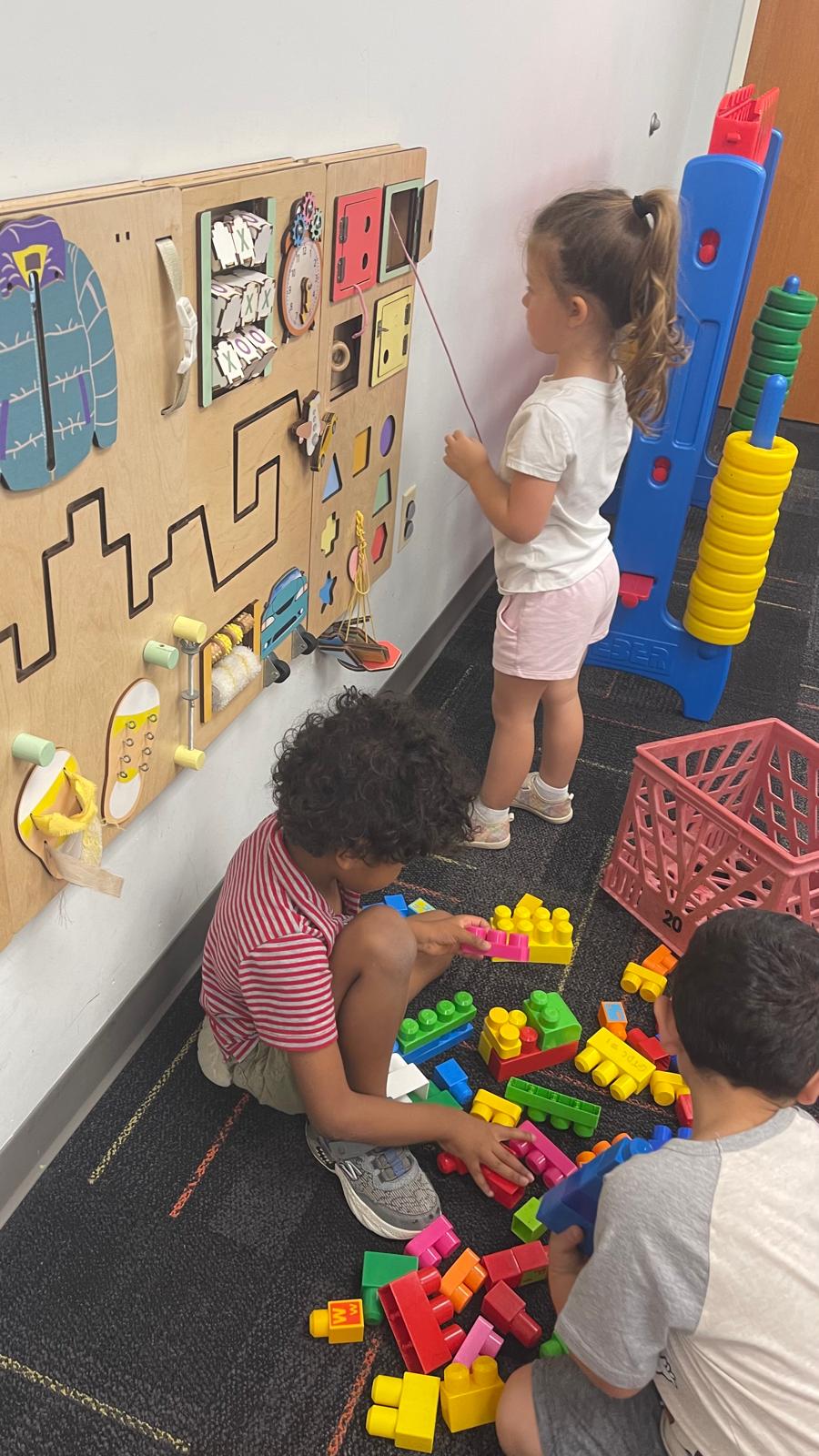 Children exploring a wooden busy board and building with blocks