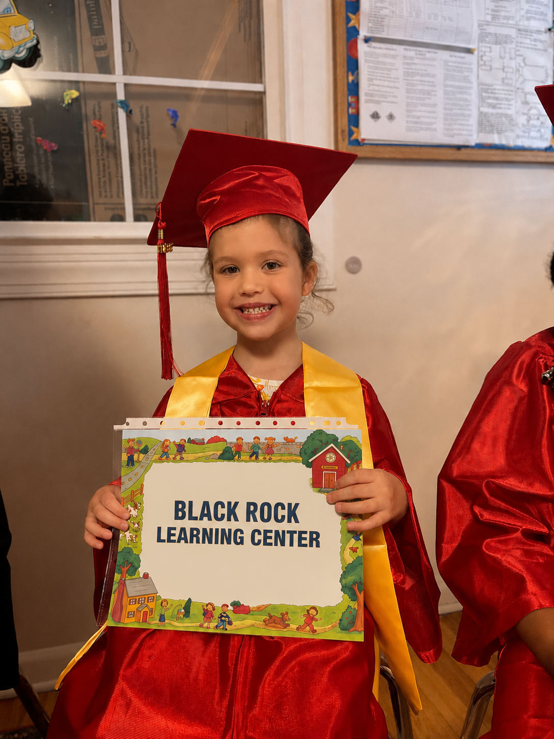 Smiling graduate holding a Black Rock Learning Center diploma